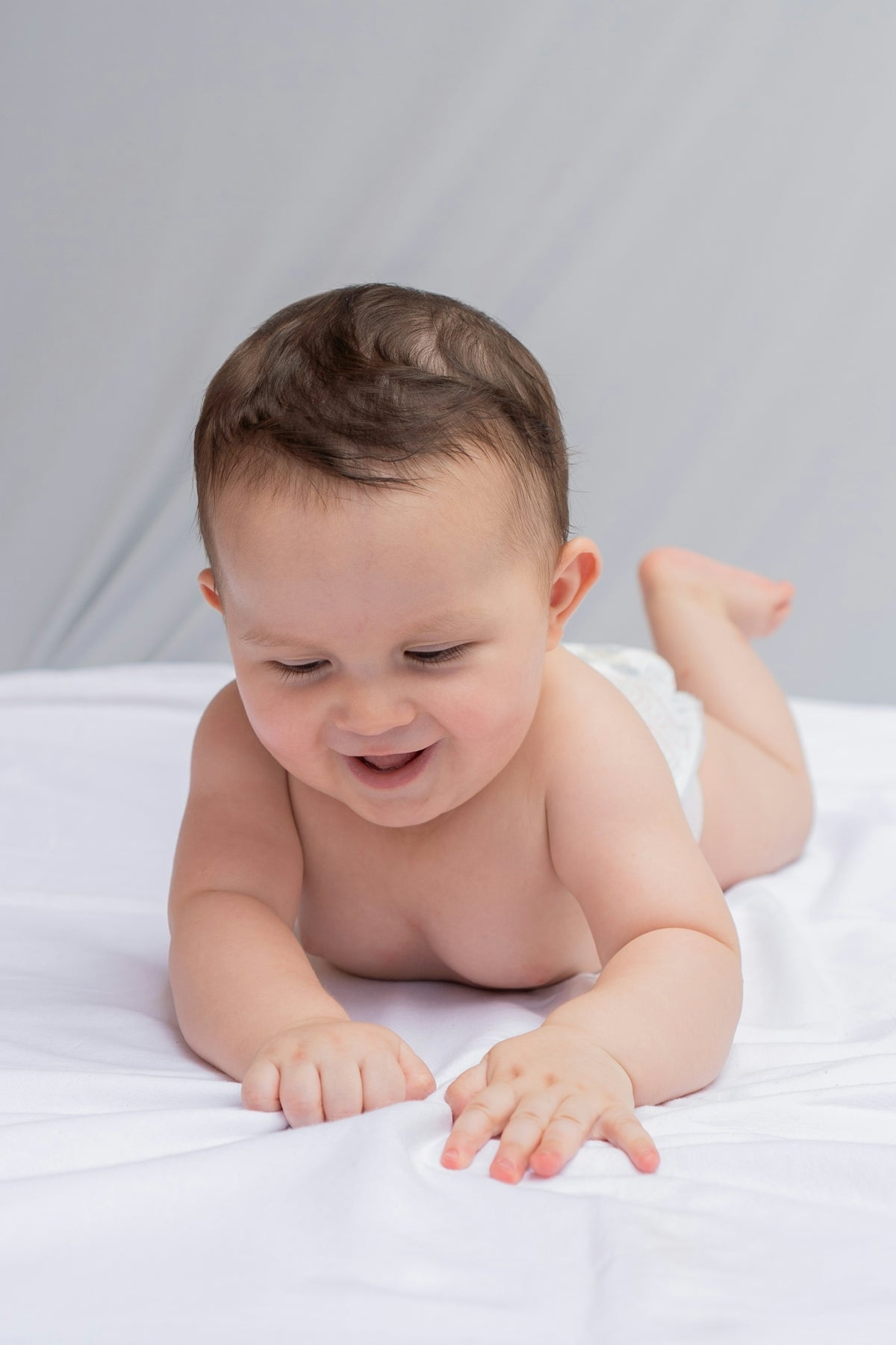 A baby is laying on a white sheet