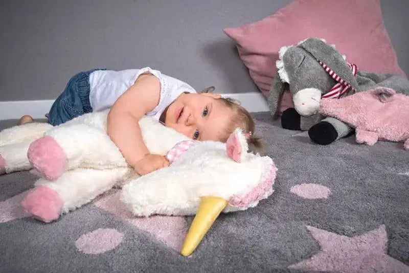 Das Mädchen liegt auf ihre Kuschelkissen Einhorn von PAT & PATTY